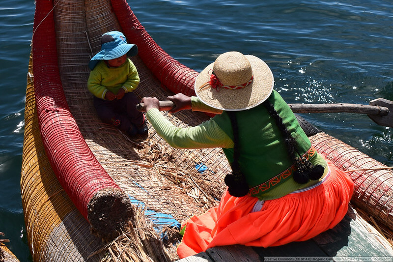 an Uro mother with her child in a totora reed boat on the Uros islands near Puno Peru in Lake Titicaca, Peru