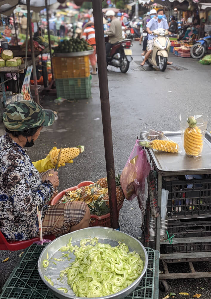 Fish Soup, Crazy Streets, and Night Markets in Saigon 20 at-work-peeling-pineapples-ho-chi-minh-city-in-vietnam.jpg
