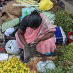 an indian grocery seller woman looking for money in her purse by the roadside in pondicherry