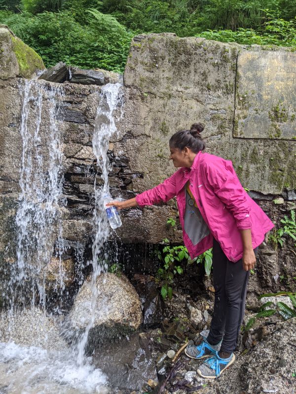 happy to drink natural water in the himalayas india 

the author standing with a water bottle near a waterfall filling water 