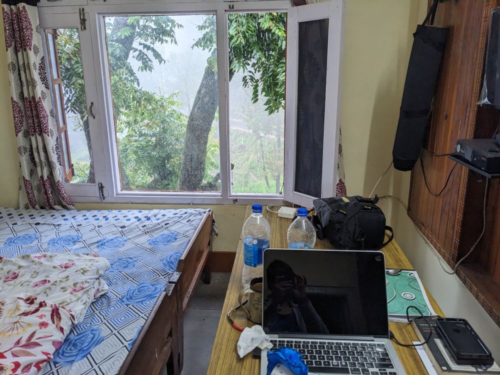 in our new home in himachal a room with table laptop bed tree outside