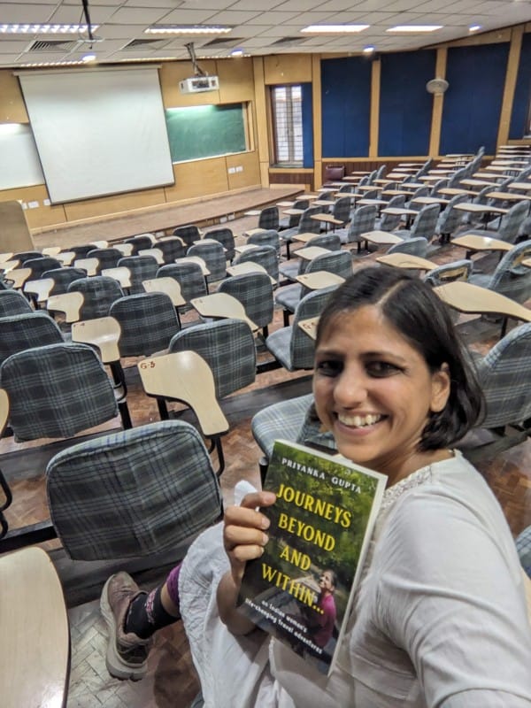 the author priyanka gupta holding her book journeys beyond and within in a lecture theatre in iit delhi