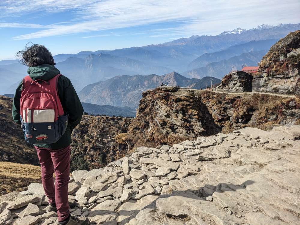 a digital nomad standing on the mountains and enjoying the view