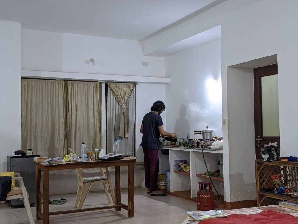 the author's partner washing dishes in a room wth tabel stove fridge etc