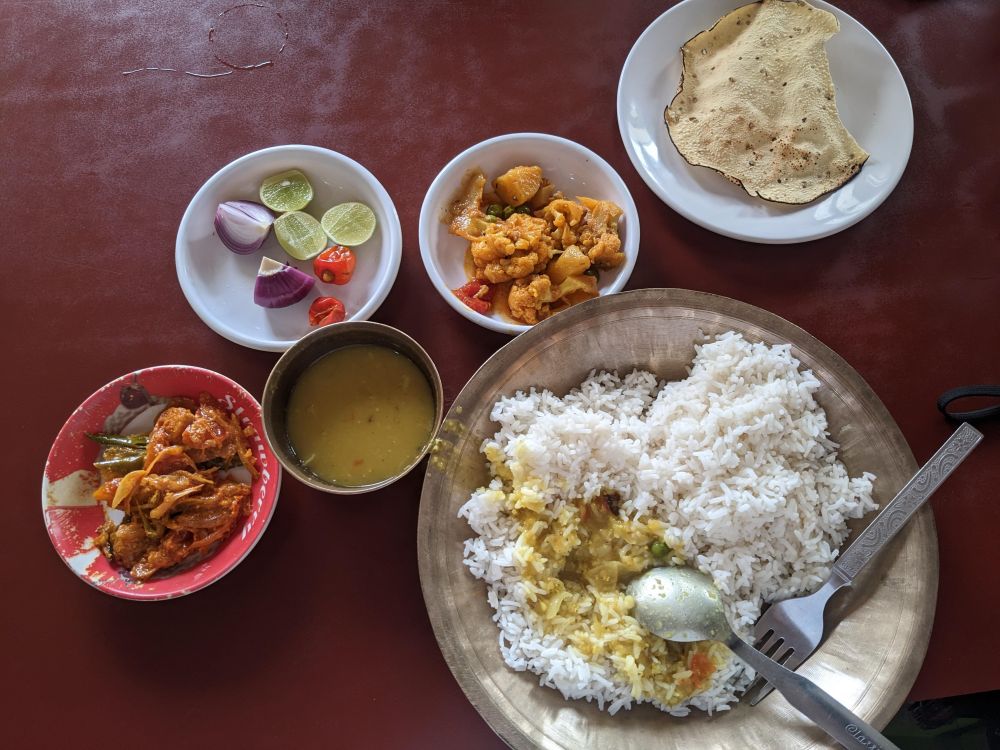 that nepali thali we loved in gangtok. dal, vegetables, chutney, onion, pickle, lemon, rice, papadum on table 