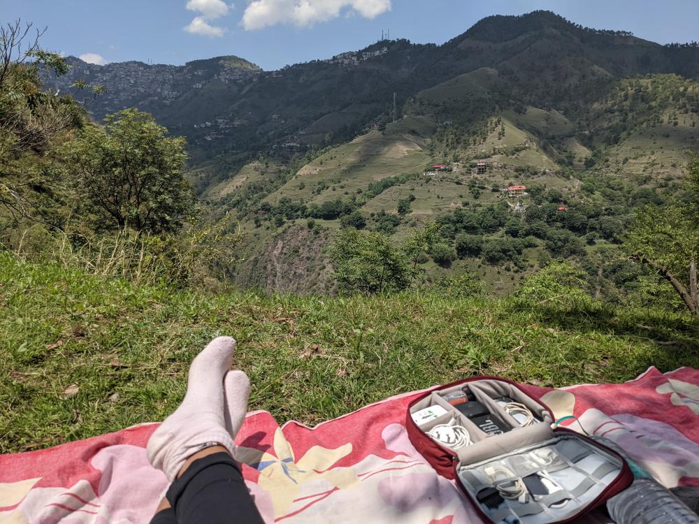 trying to work from the mountains. image shows cables and feet on a grassy mountain hinting that the people whose faces arent visible are working