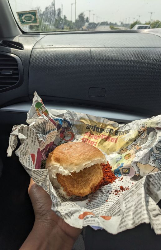 a vada pav, maharashtran snack on newpaper in car