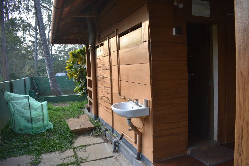 an outdoor toilet, washbasin, nestled in a garden