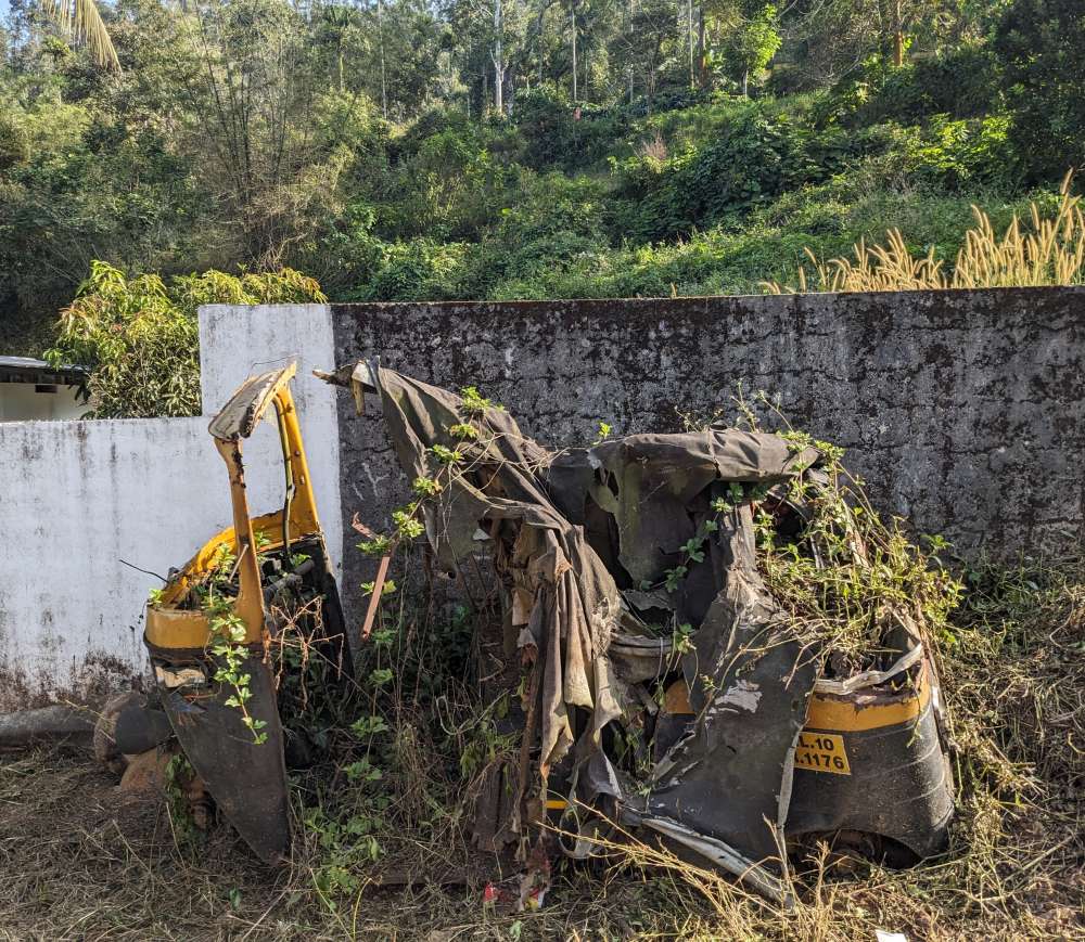 an auto rickshaw deteriorated and now part of the forest covered with vines