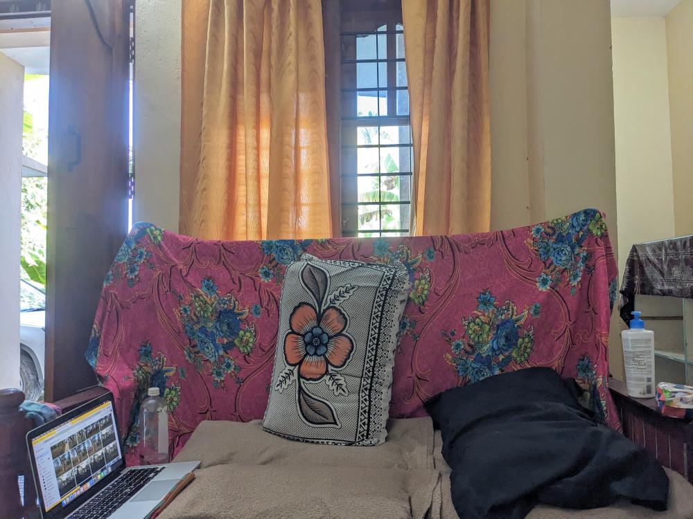 a couch with laptop and pillows and covers, my makeshift work desk in a guesthouse in Wayanad village kerala