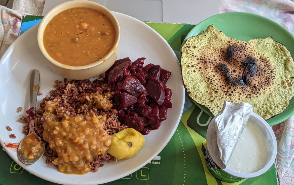 a plate of homemade brown rice, dal, beetroot fry, and papad