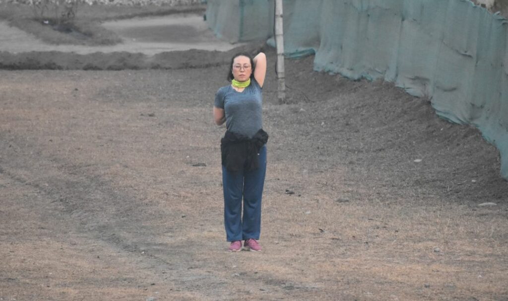 a woman exercising stretching her arms on an open field