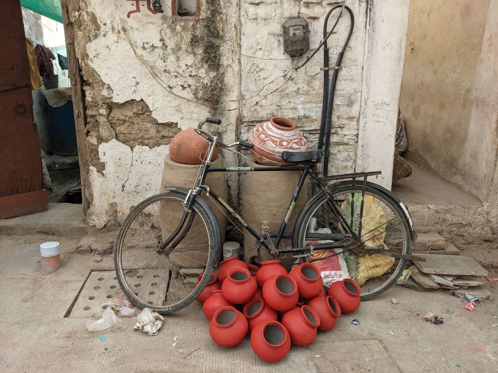 a simple lane of udaipur with bicycle and red pots of clay tiny